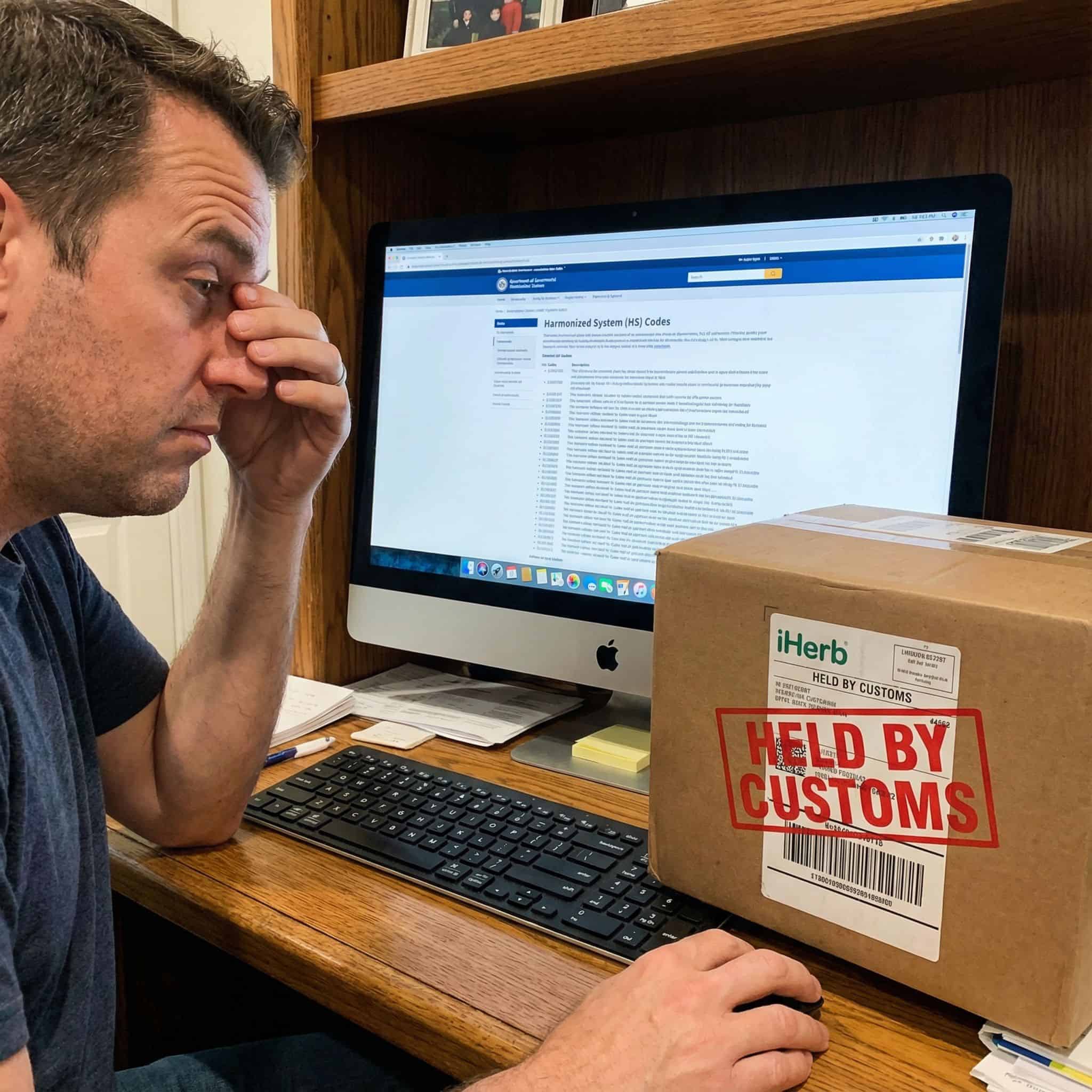 iHerb라고 적힌 소포가 적하목록 번호가 뜬 컴퓨터 화면을 보며 당황한 고객과 함께 세관에 붉은 압류 도장이 찍혀 있습니다.